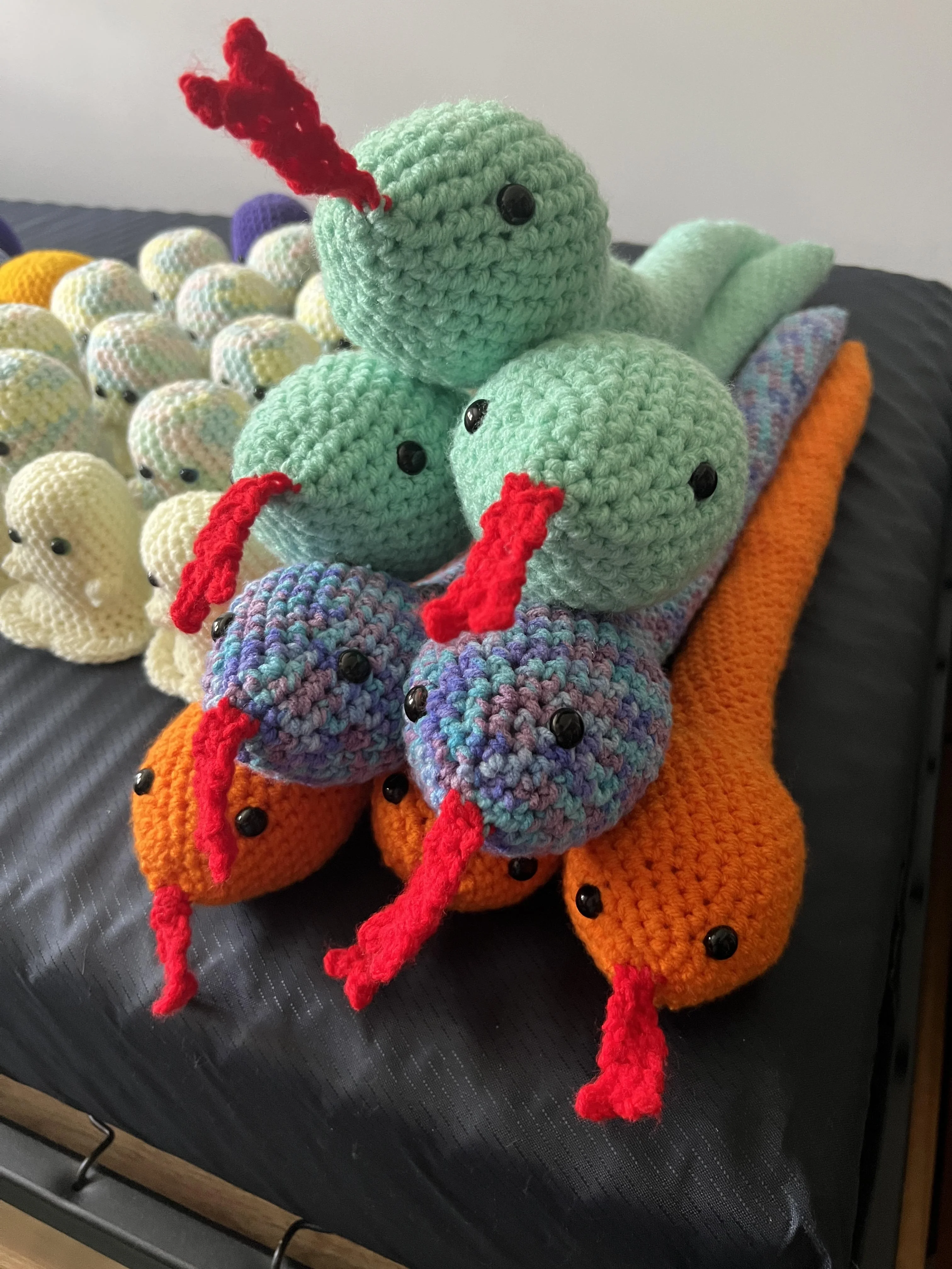 five different colored crochet snakes on top of each other